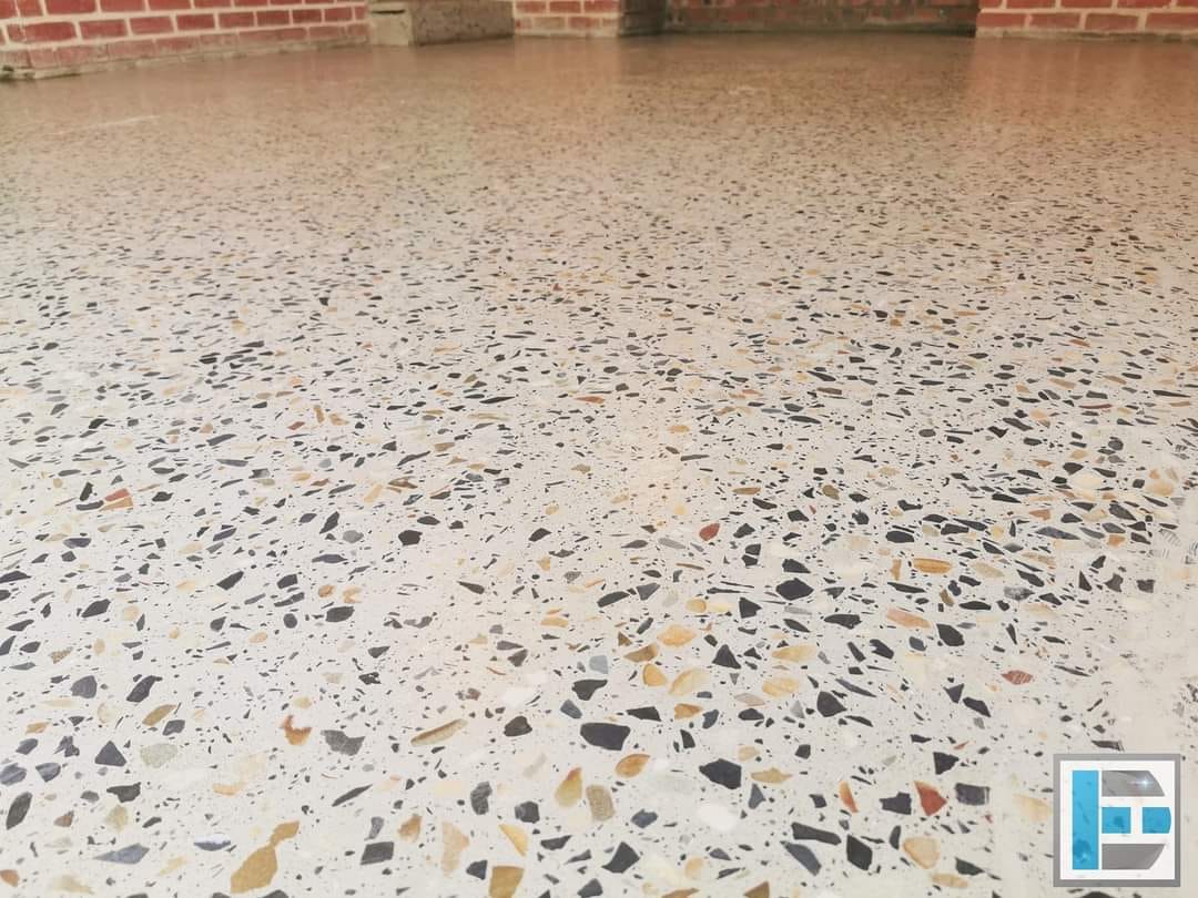 Close-up of a polished floor with natural stone aggregate in black, ochre and cream